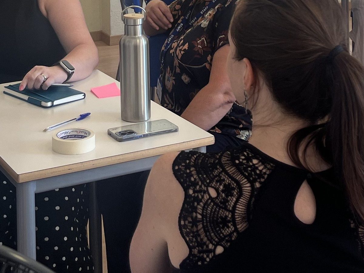Teachers around a table at Andersen International School, Milan, one with a notebook open, framed from behind